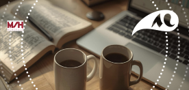 deux tasses de caf&eacute;s, un livre et un ordinateur portable sur un bureau